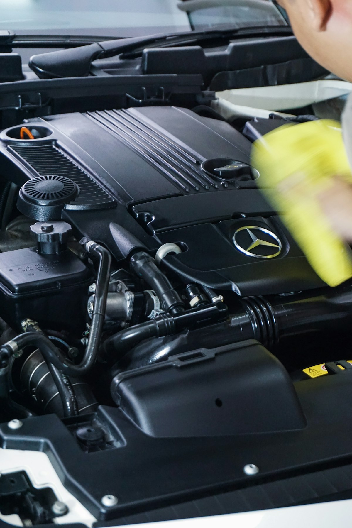Hand wiping down a clean engine bay with a microfiber cloth