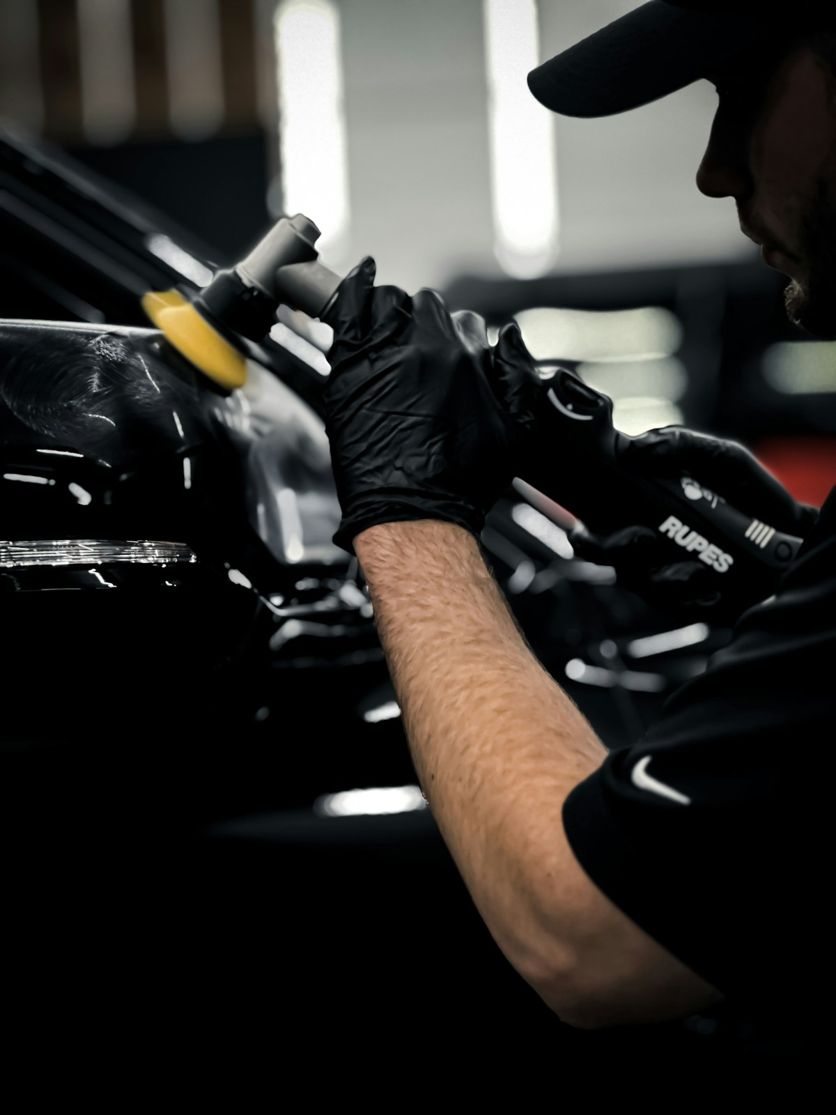 Detailer using a dual-action polisher for paint correction on a dark colored car