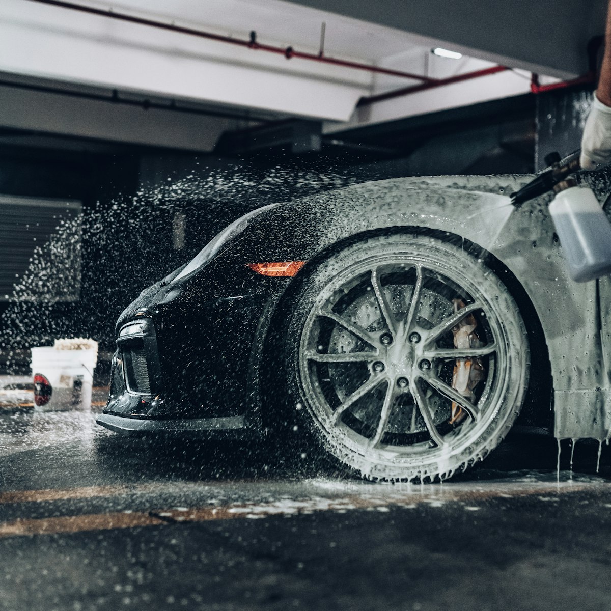 Sports car covered in foam during a hand wash in a garage bay
